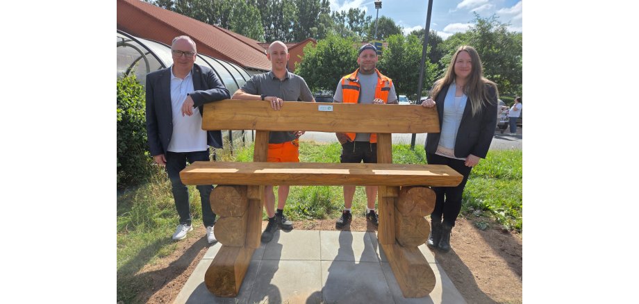 Foto: Baumelbank aus Holz, dahinter v.l.n.r.: Bürgermeister Klaus Wagner, Marcel Völpert (Bauhofleiter), Daniel Vesper (Bauhof) und Maria Bax (Leiterin EAM-Regionalzentrum Mitte
