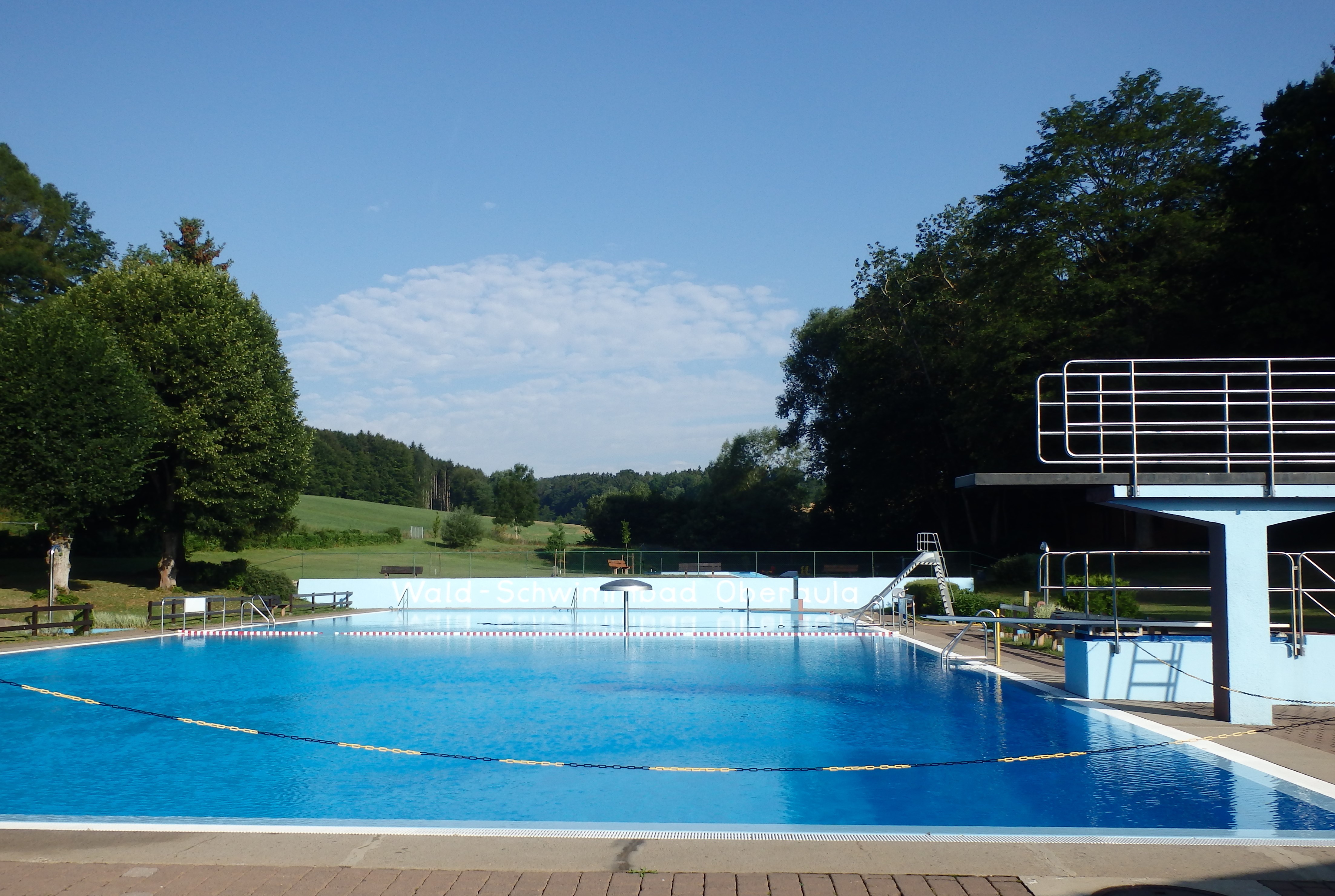 Waldschwimmbad; blauer Himmel; Sprungturm im rechten Bildrand
